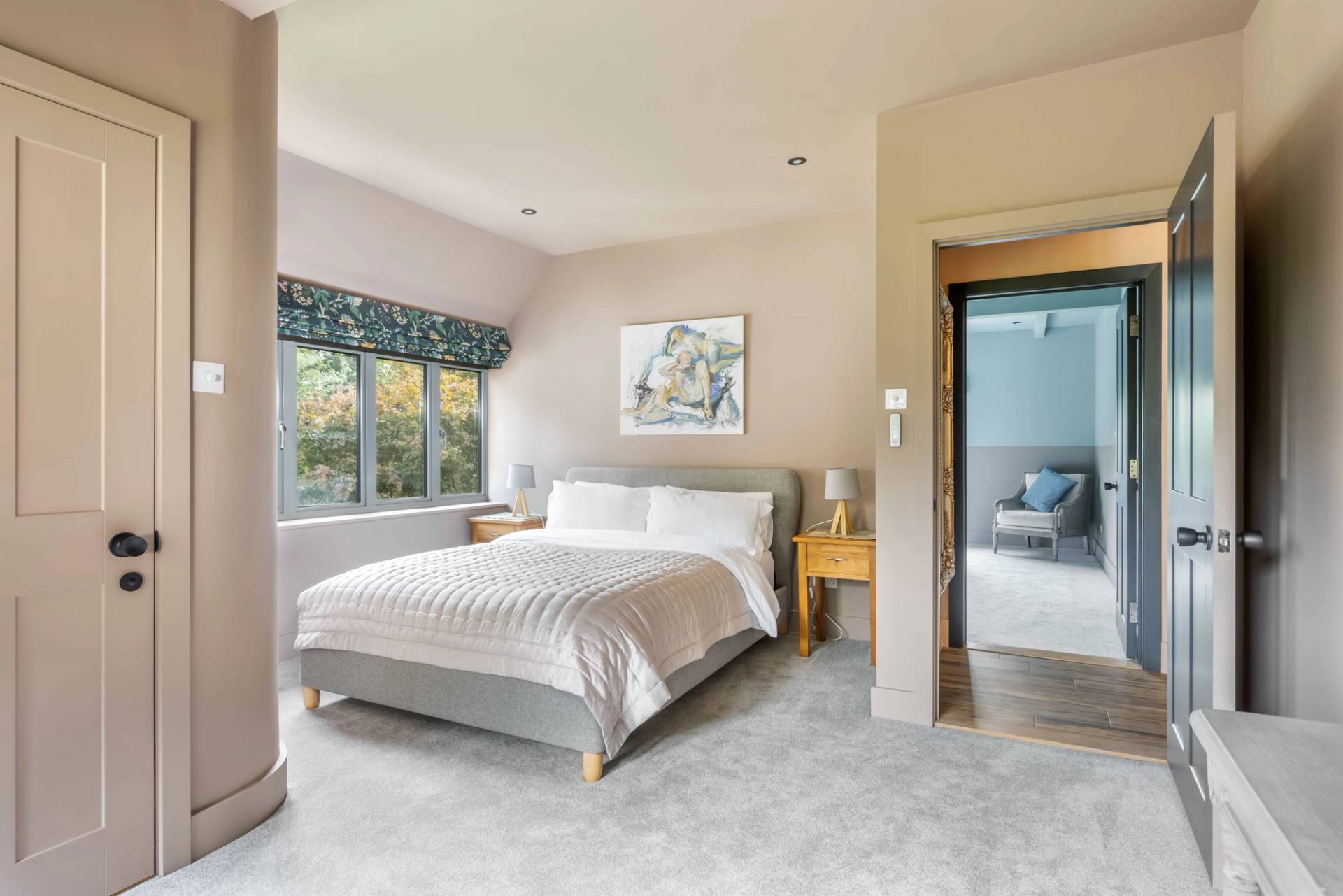 Bright guest bedroom suite with plush grey carpets, oak side tables, and leafy rural views, Love Locations GU27.