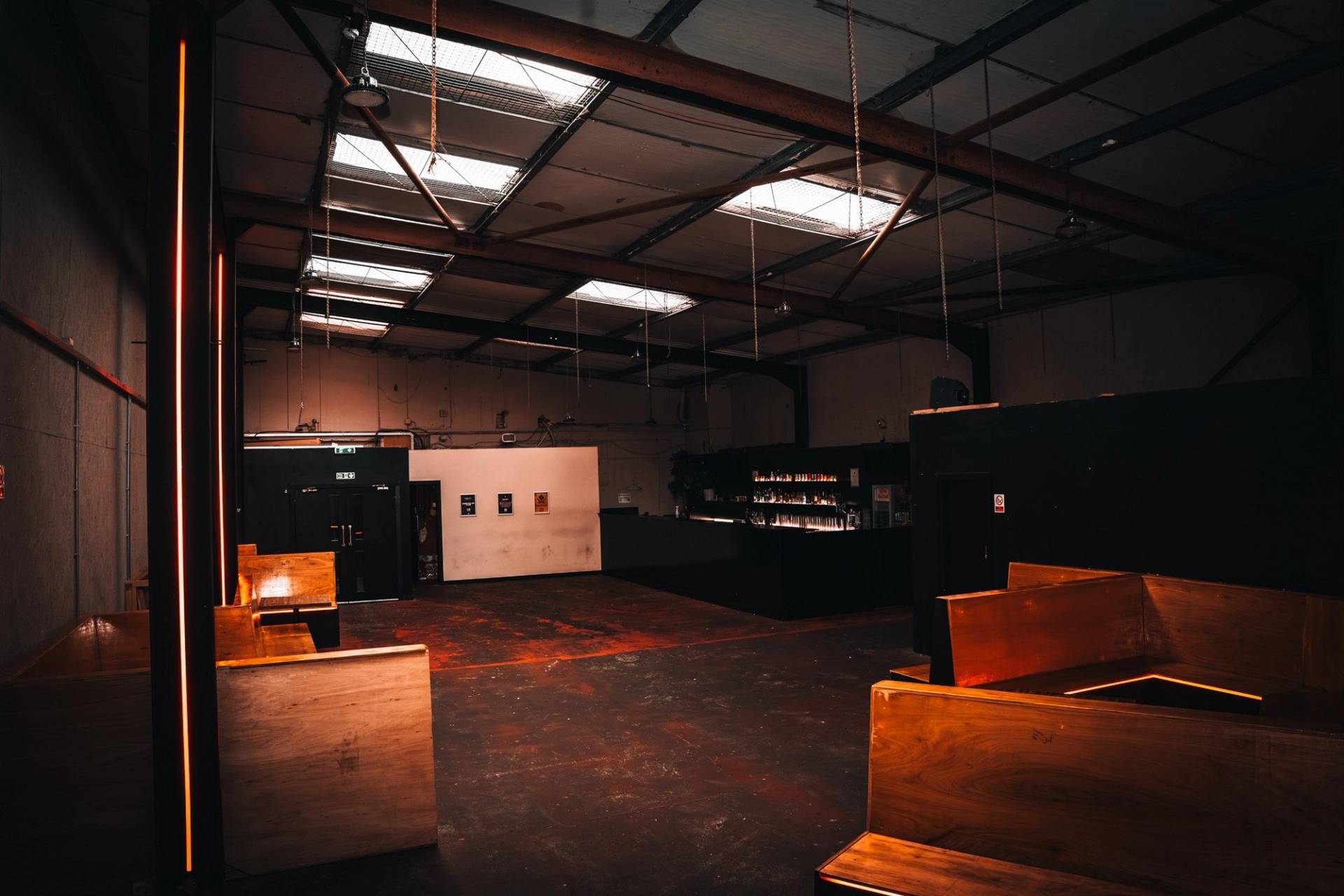 Large open-plan warehouse hall featuring skylights, polished concrete floor, and perimeter bar counters in Manchester M3 via Love Locations.