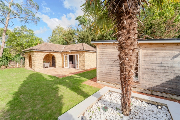 Lawn garden view showing a tropical palm tree, outdoor pool, and garden outbuildings, Love Locations RM11.