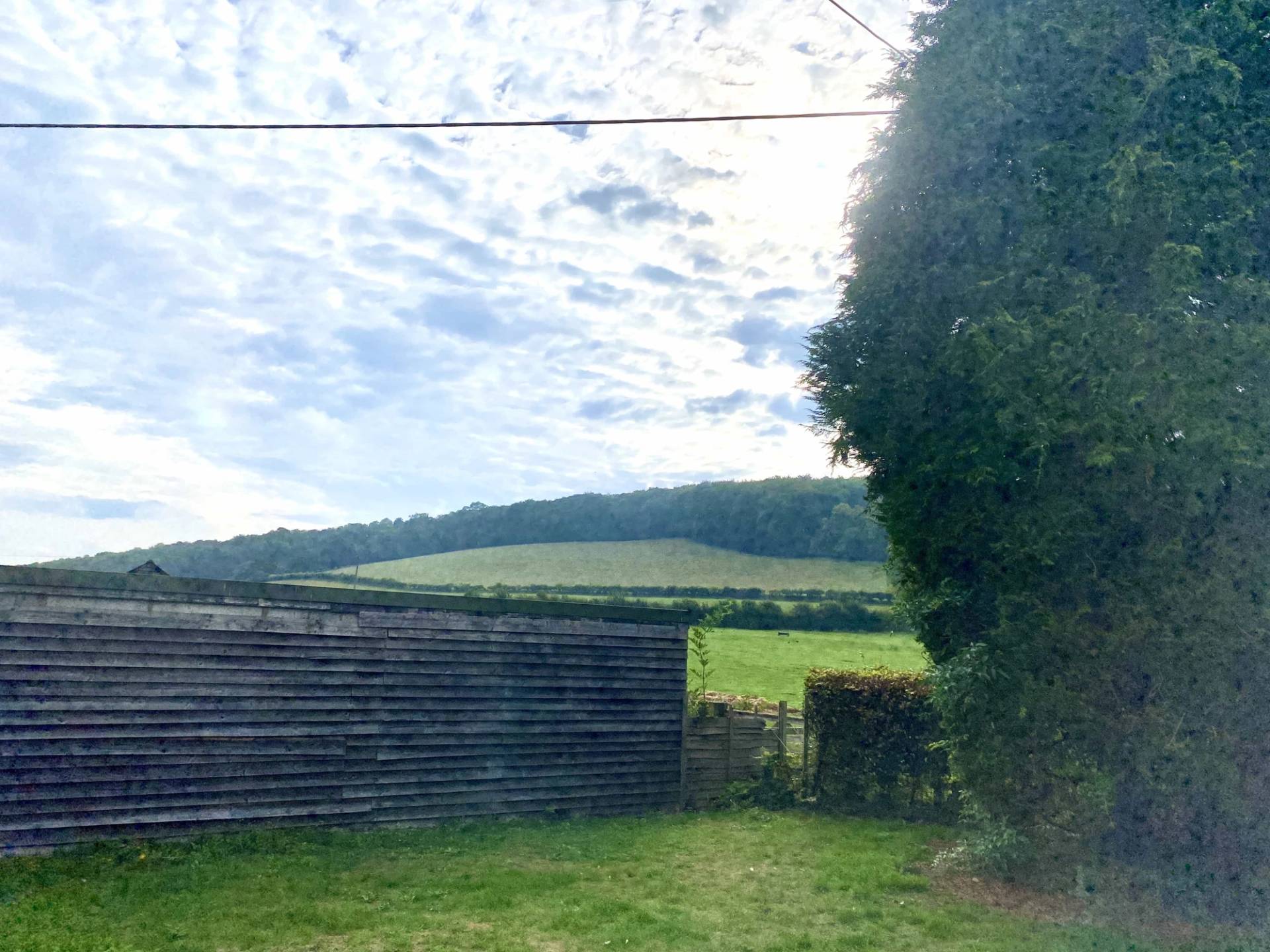 Breathtaking outdoor landscape view looking out from the cottage gardens across a sweeping green valley surrounded by dense woodland, the ultimate rural backdrop for commercial outdoor productions via Love Locations.