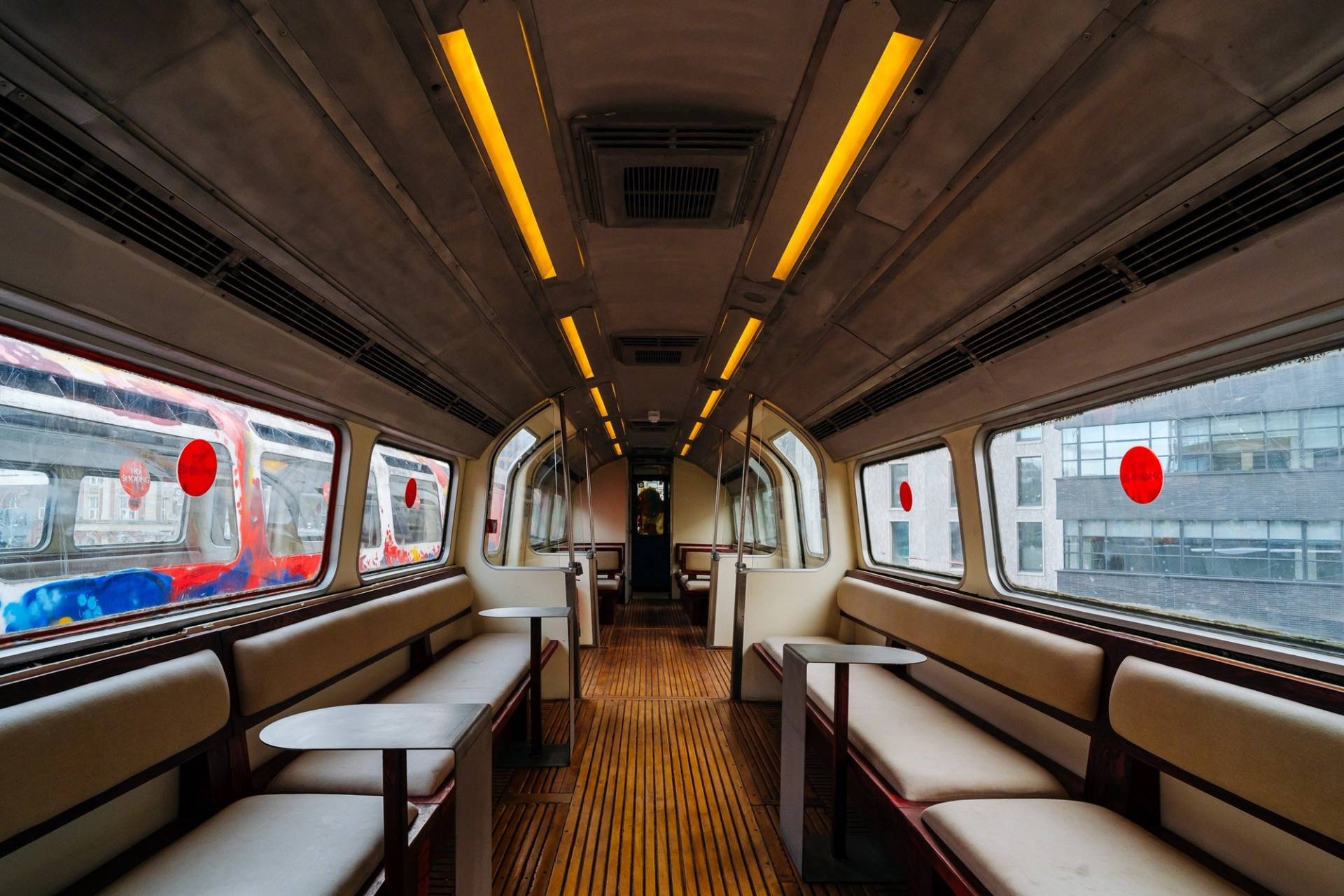 Unique train carriage lounge shoot space featuring leather banquette seating, wooden table tops, and linear overhead lighting from Love Locations.