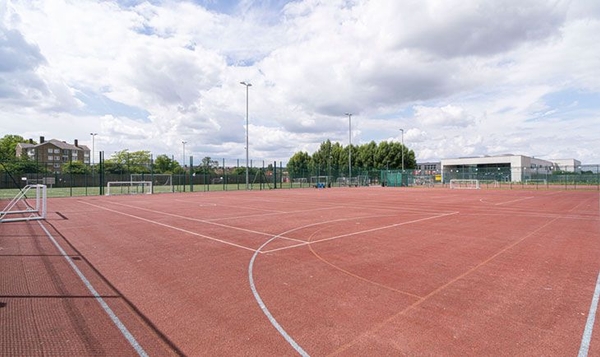 Love Locations outdoor tarmac sports court South East London: Large red asphalt multi-use games area with painted court boundaries, excellent for urban youth dramas and sports filming.