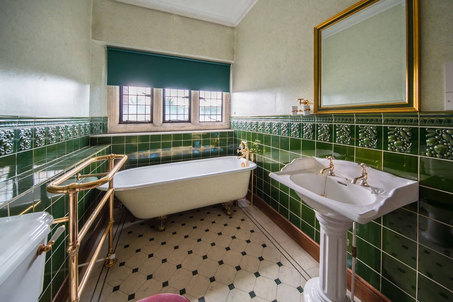 Vintage green tiled bathroom location house featuring a freestanding clawfoot bathtub and pedestal basin via Love Locations.