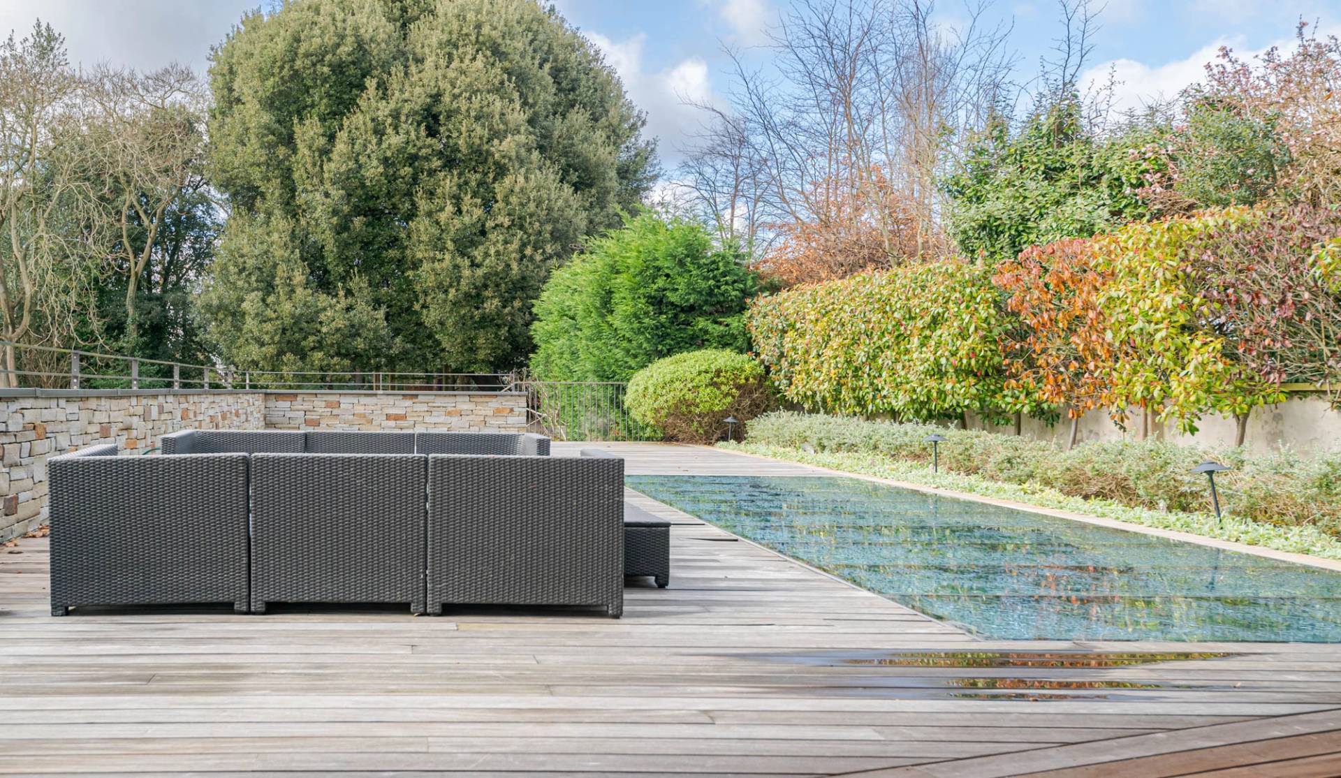 Outdoor timber decking terrace set with dark rattan sofa seating and garden views, Love Locations KT2.