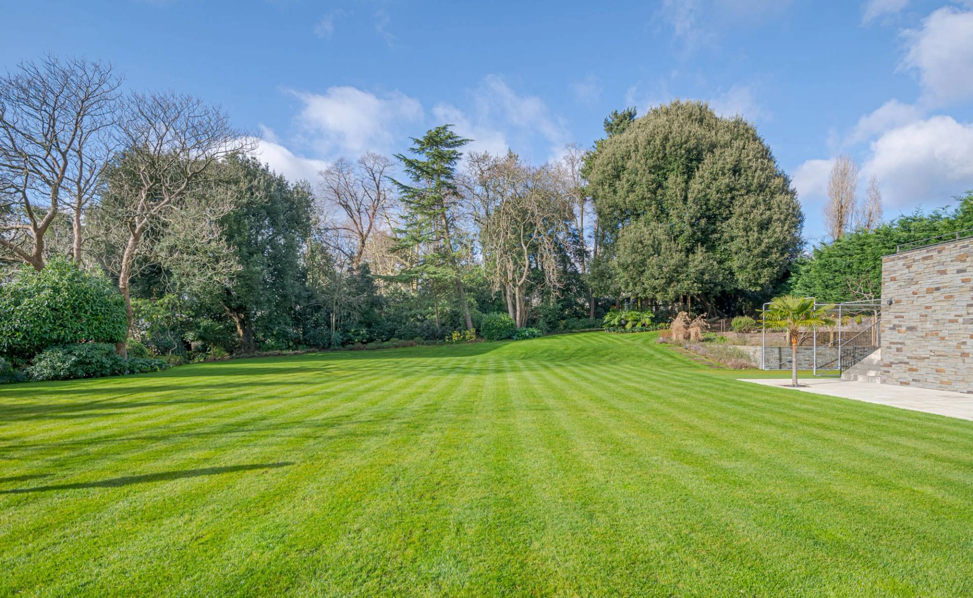 Expansive manicured lawn garden surrounded by mature trees in a private Kingston location home, Love Locations KT2.