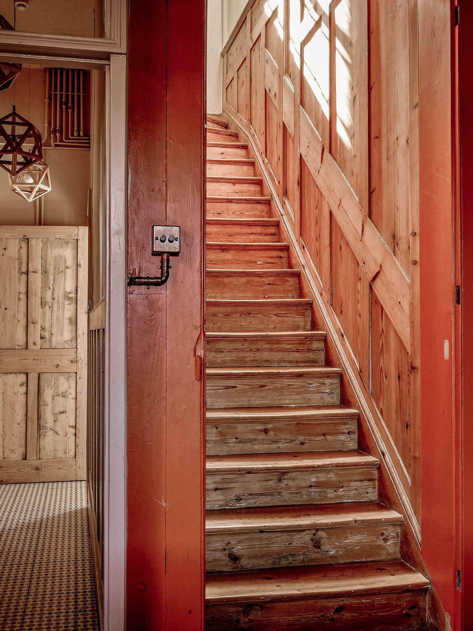 Raw timber staircase with exposed wooden steps leading up past warm orange wall panelling, Love Locations ME13.