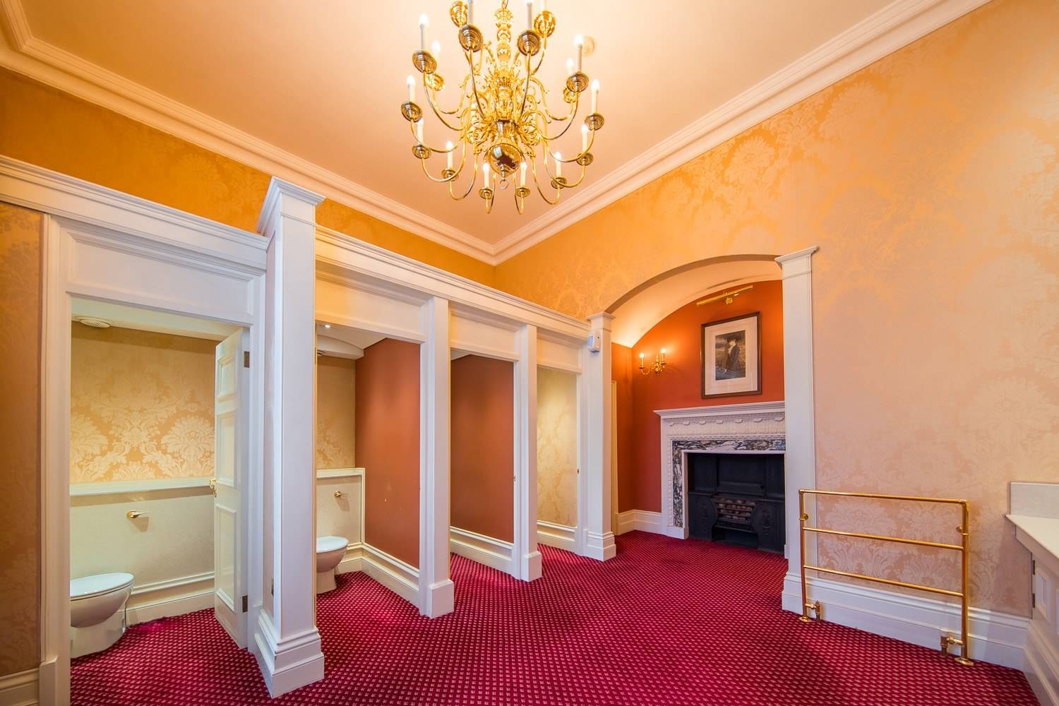 Historic dressing room and anteroom featuring white architectural archways, red carpet, and a marble fireplace surround through Love Locations.