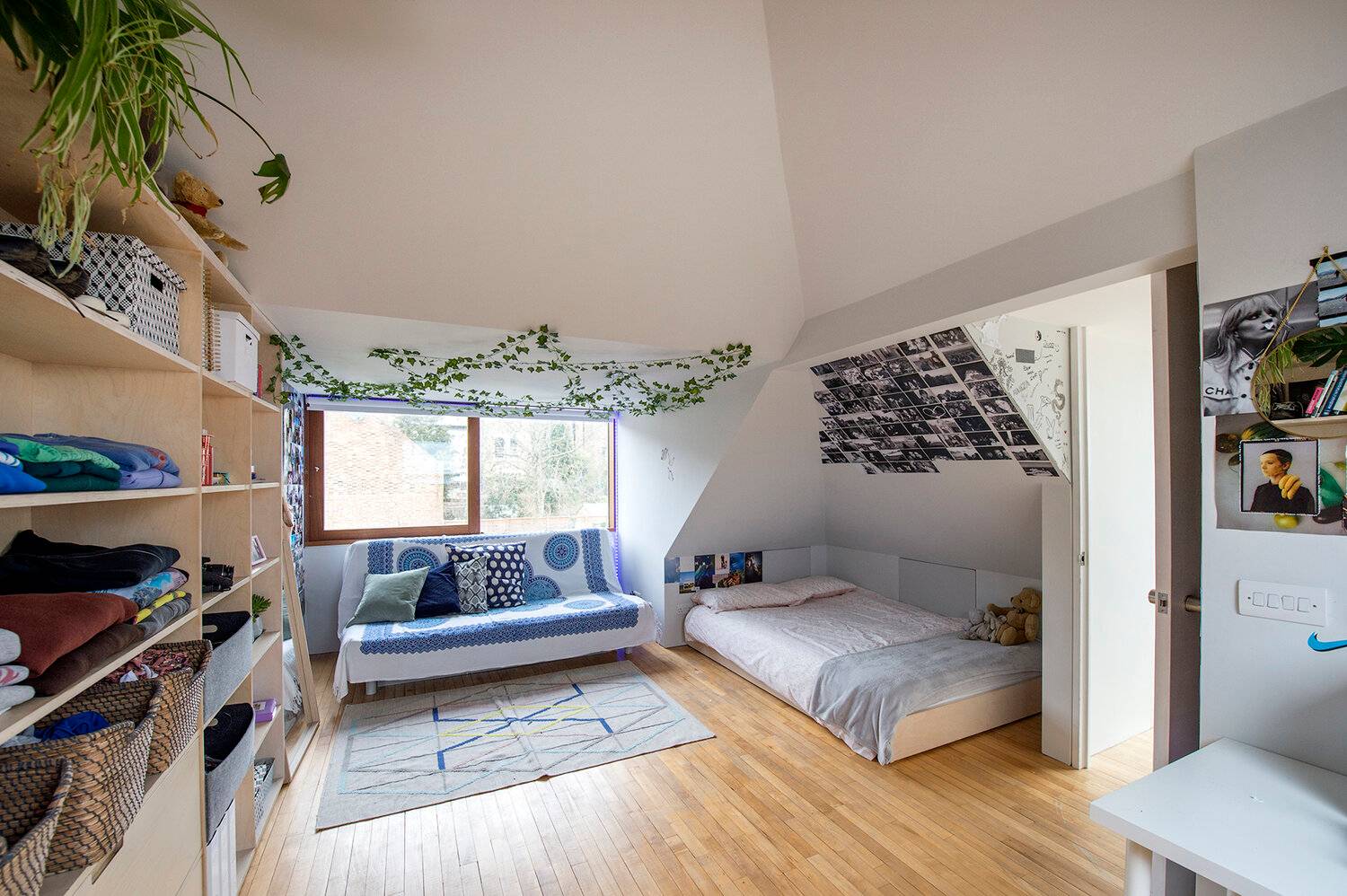 Attic loft room with sloped ceilings, roof skylight windows, blue sofa bed, and wooden floorboards, Love Locations SE23.