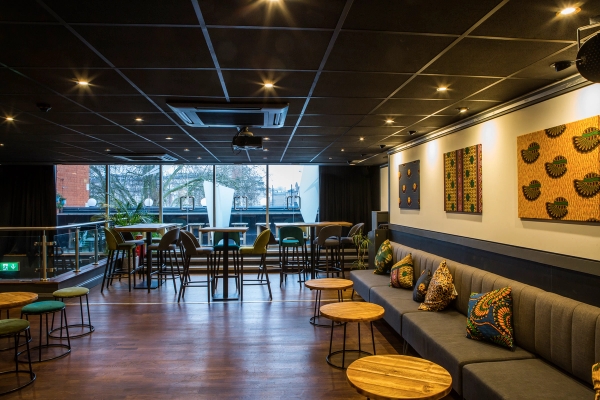 Wide view of the main upstairs event room looking towards large glass windows and elevated drinking counters at The Ritzy Brixton, Love Locations.