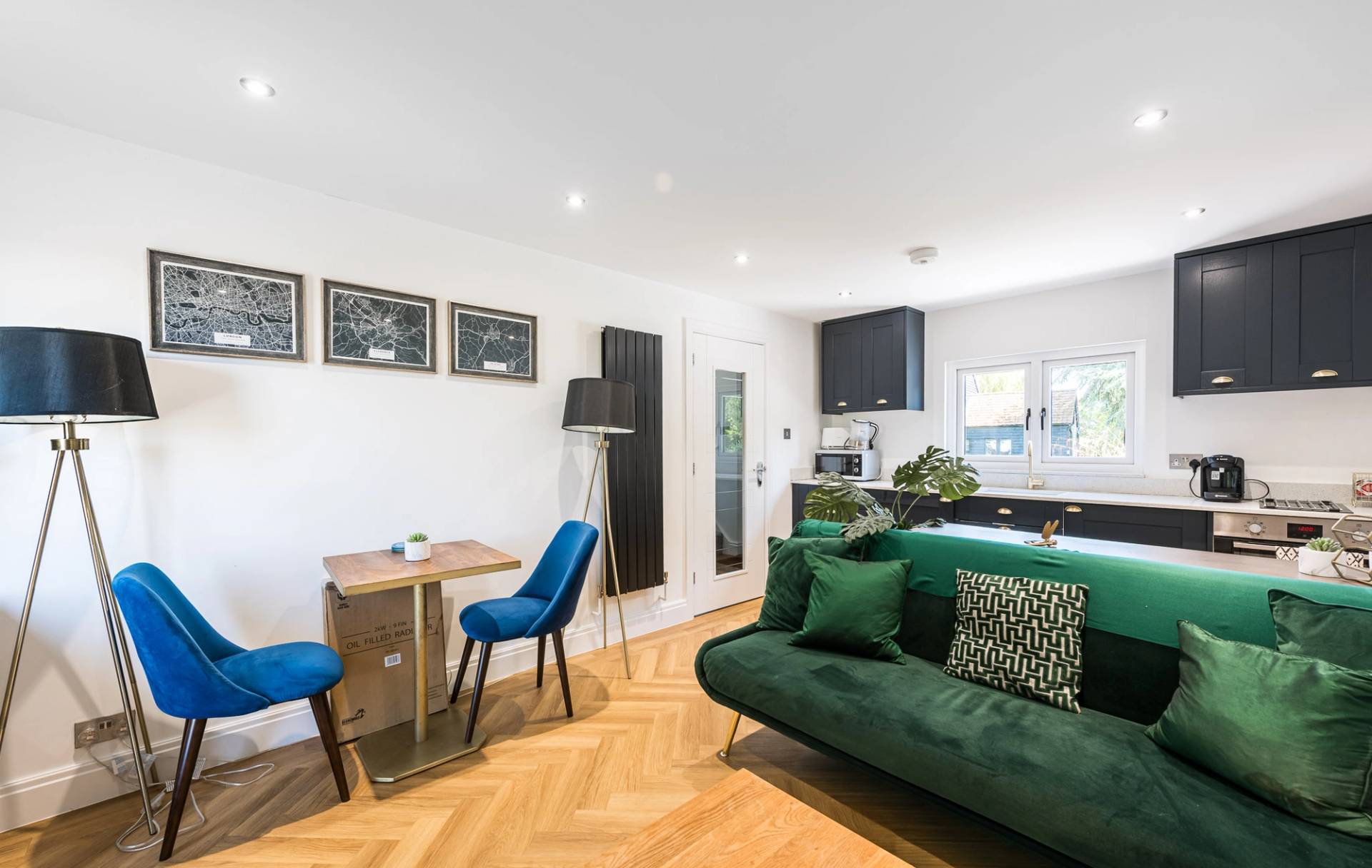 Self-contained modern annex apartment living room featuring a rich green velvet sofa and herringbone flooring, Love Locations.