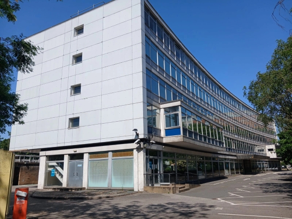 Brutalist style office building exterior film location in Watford WD18 available from Love Locations, showcasing a white panelled facade, grid windows, and an entrance lobby.