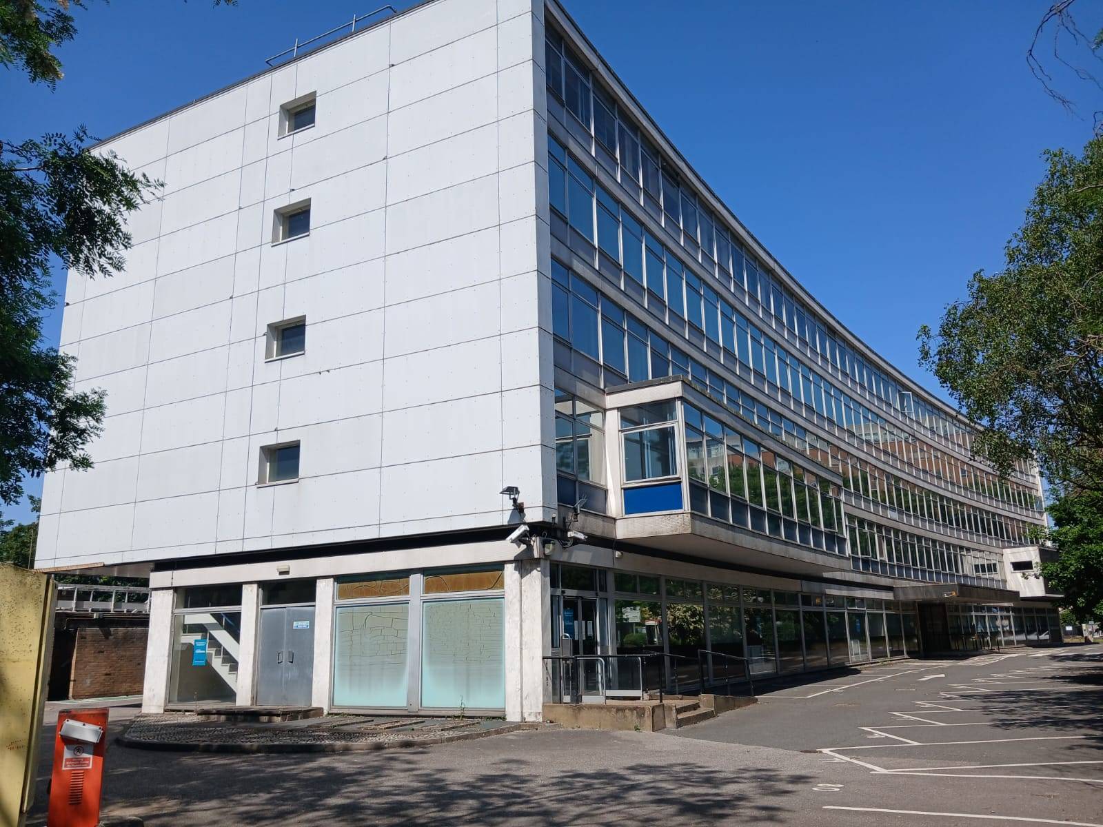 Brutalist style office building exterior film location in Watford WD18 available from Love Locations, showcasing a white panelled facade, grid windows, and an entrance lobby.