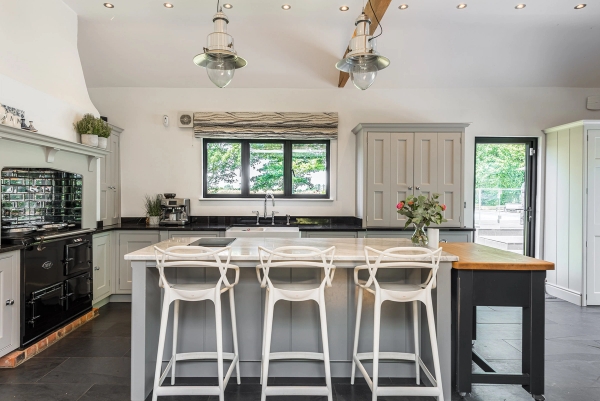 Contemporary kitchen island with white breakfast stools inside a premium Essex barn conversion for film hire, Love Locations.