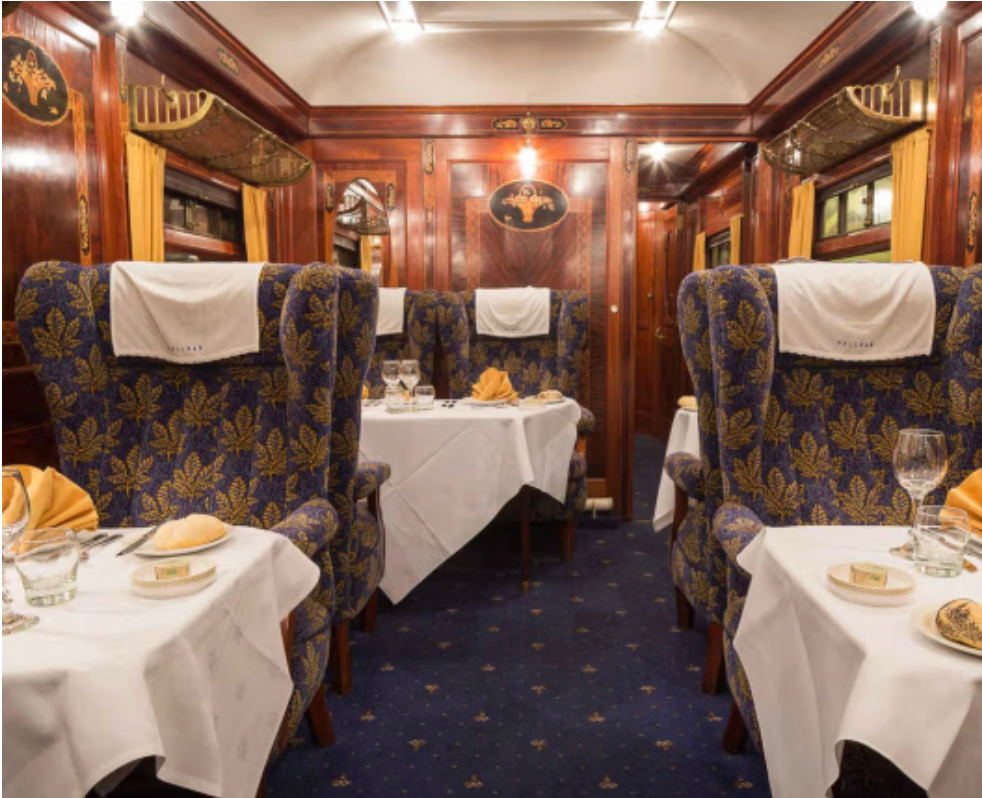 Luxury heritage train dining carriage dressed for an elegant Christmas dining event with white tablecloths and vintage interiors.