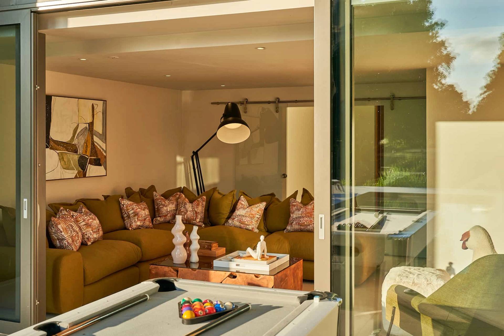 Cozy entertainment lounge room featuring an olive green sectional sofa and modern floor lamps, Love Locations SO21.