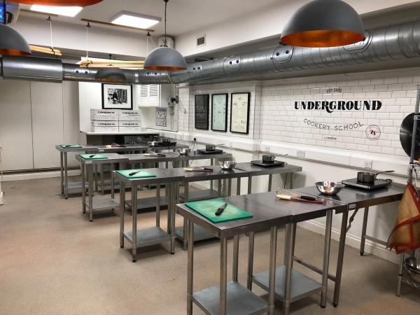 Empty cooking workshop class setup with individual chopping boards and green knives for lifestyle video shoots, Love Locations.