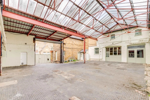 Industrial courtyard location with a textured glass roof and steel beams for commercial filming in Richmond, TW10 via Love Locations.