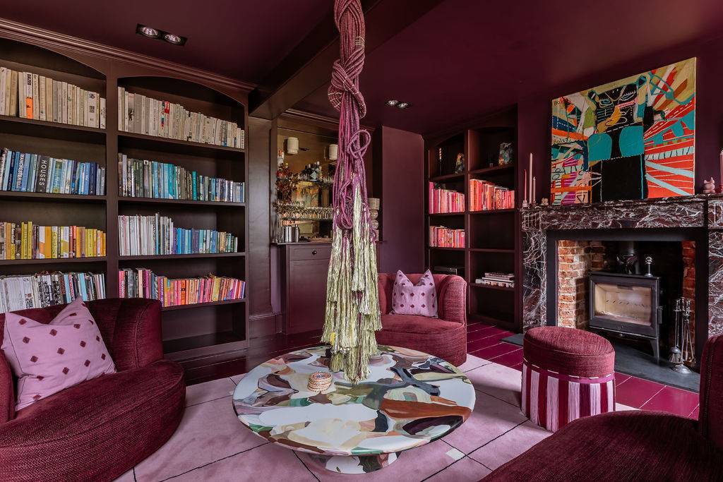 Moody dark purple salon interior highlighting a central round marble coffee table and cozy armchair nooks from Love Locations.
