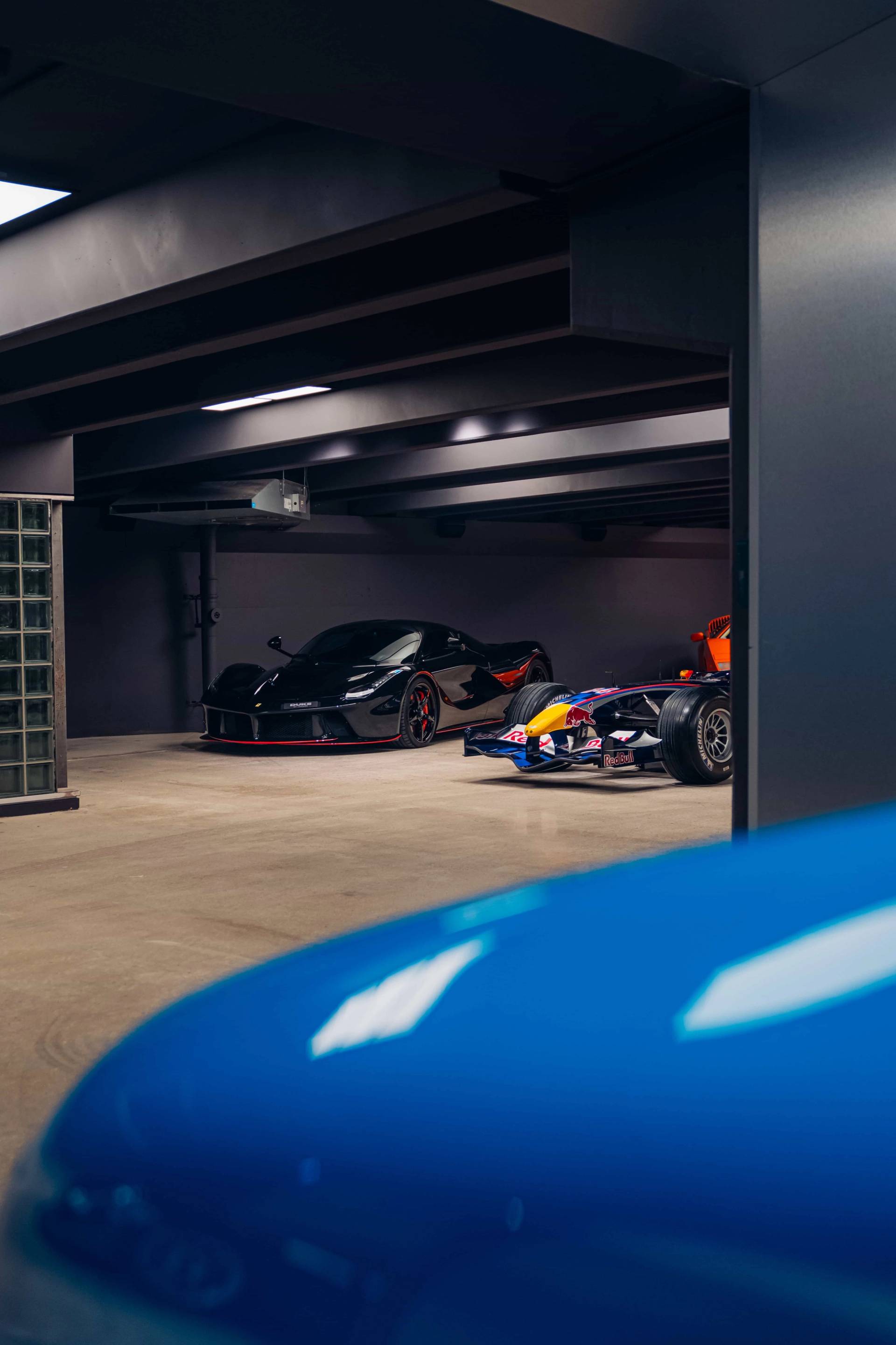 Elevated perspective looking into a dark underground bunker holding rare hypercars and race cars via Love Locations.