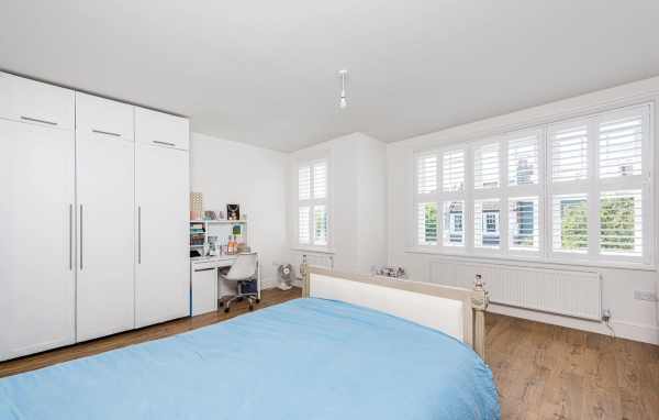 Contemporary residential bedroom location featuring built-in white wardrobes and an integrated home office desk setup, Love Locations.