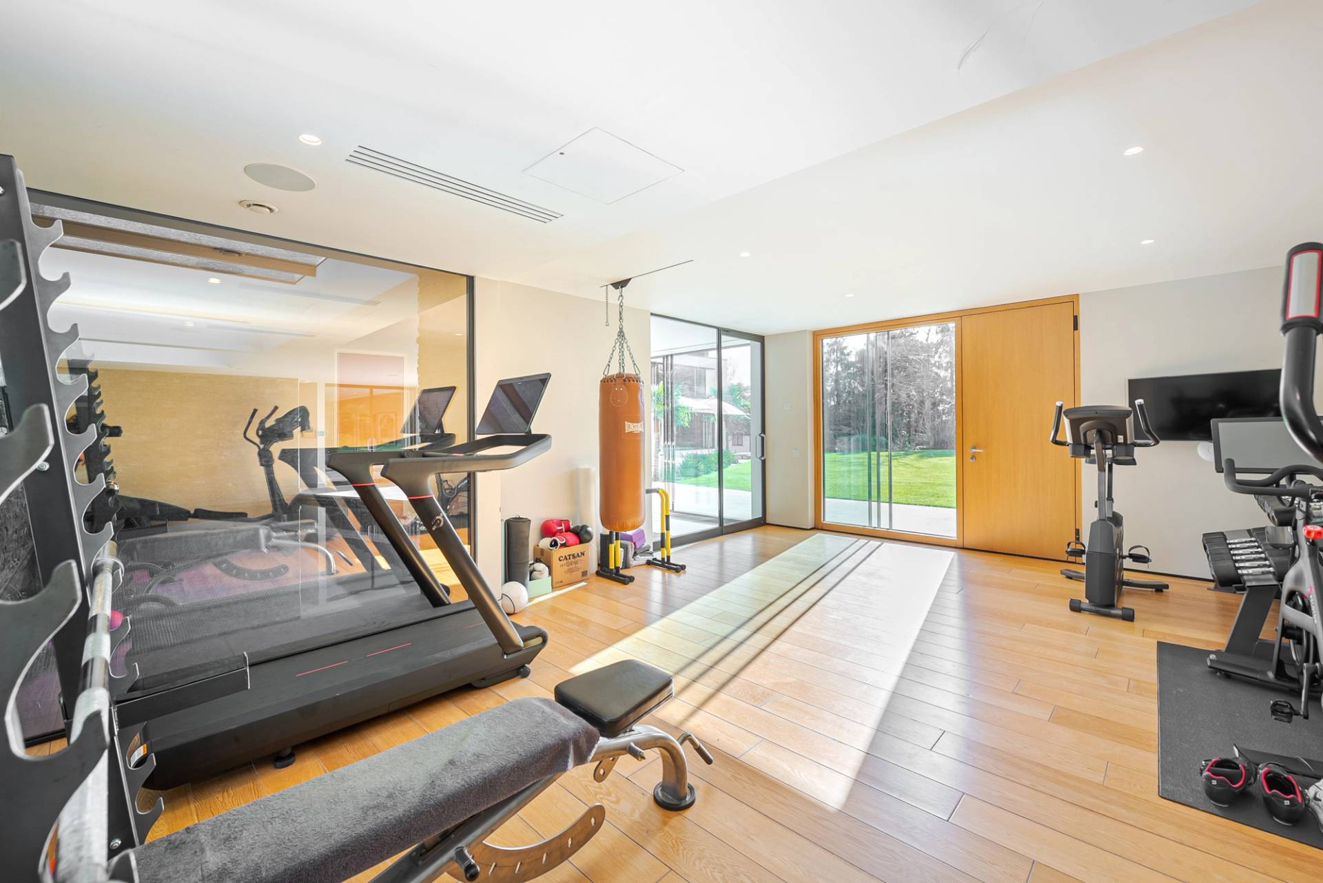 Fully equipped home gym studio with cardio machines, weight bench, and floor-to-ceiling garden windows, Love Locations KT2.