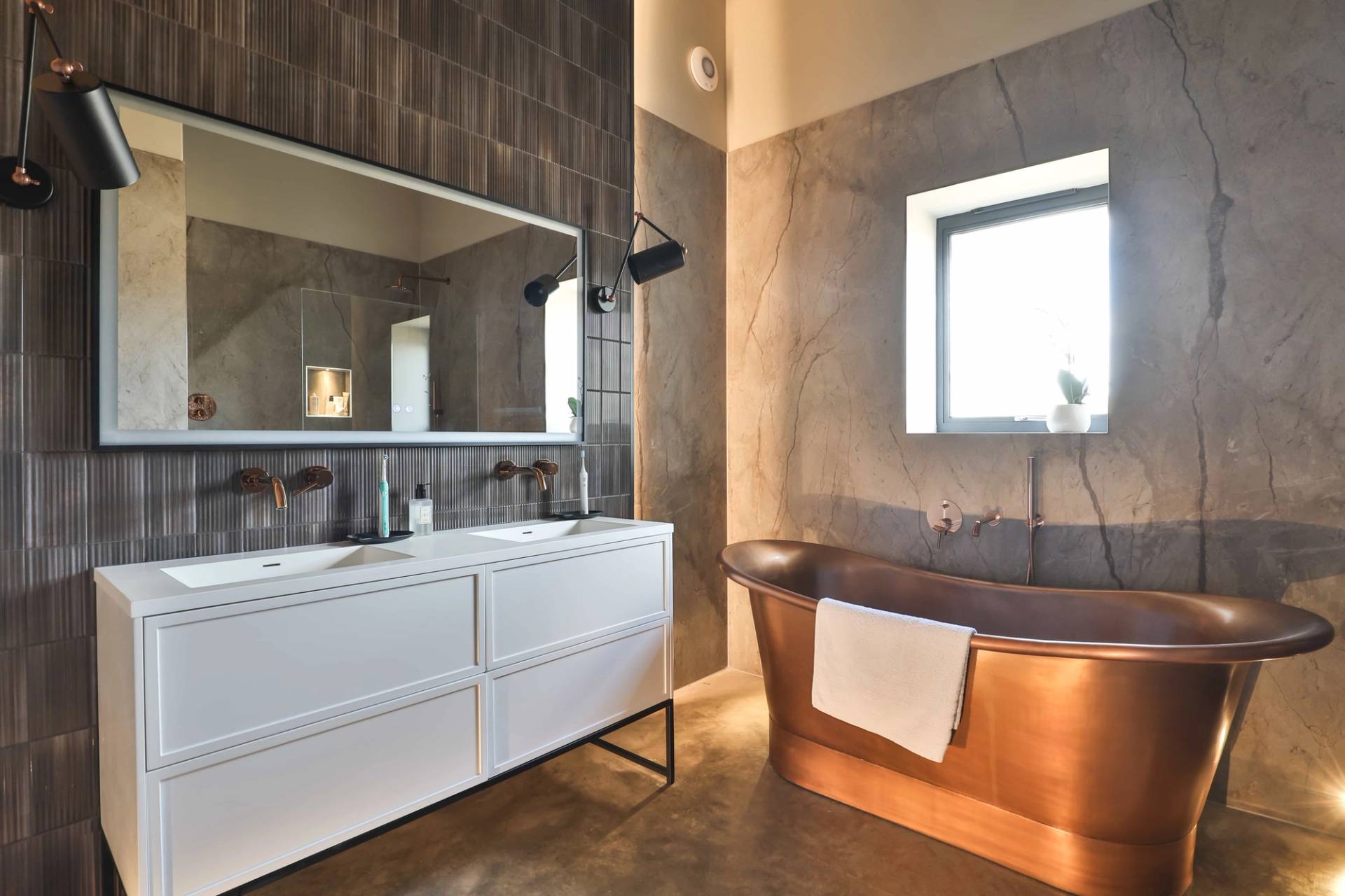 Master ensuite bathroom with a freestanding copper soaking bathtub, double sink vanity, and marble walls, Love Locations CV23.