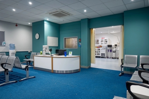 Curved hospital reception desk set in a blue carpeted waiting room area, Love Locations UB4.