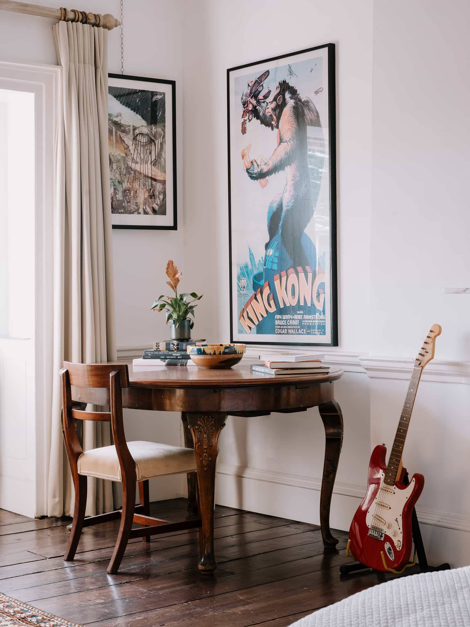 Music room corner with a vintage wooden dining table, electric guitar, and classic framed poster art, Love Locations RG42.