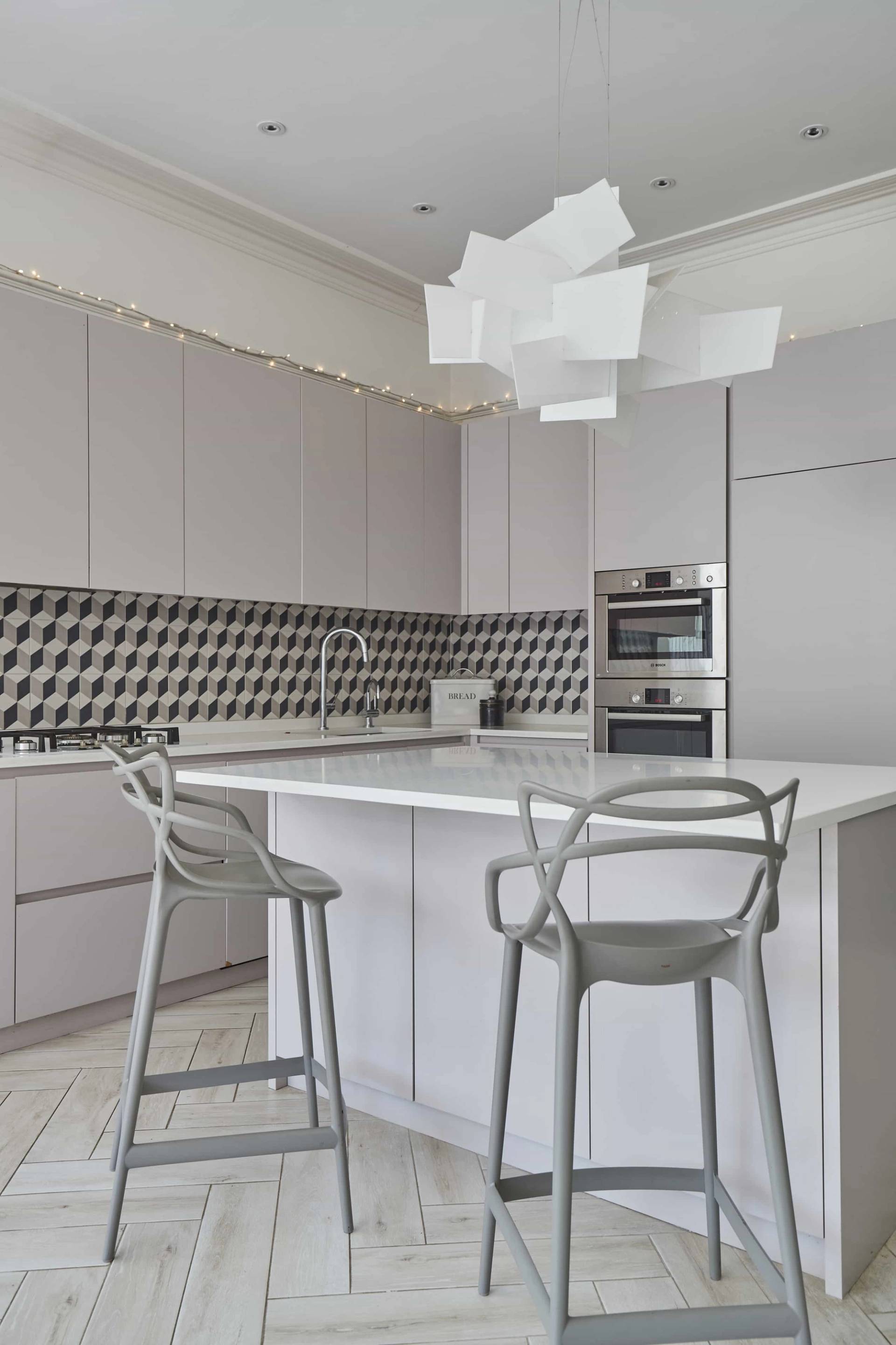 Modern white kitchen with monochrome geometric tiled backsplash, white quartz island, and modern pendant lights, ideal for food media ads, Love Locations.