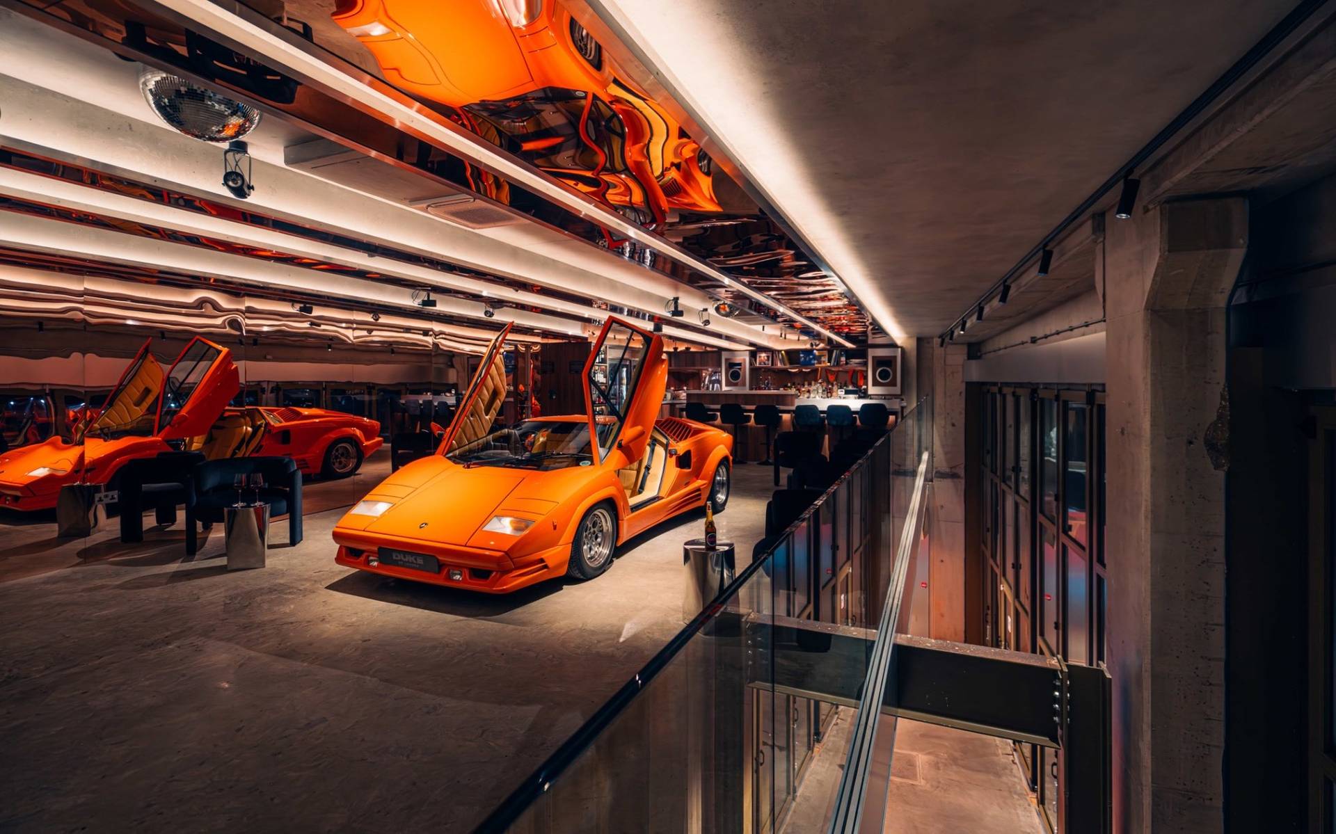 Elevated perspective looking down onto an orange Lambo parked inside a multi-level listening bar from Love Locations.