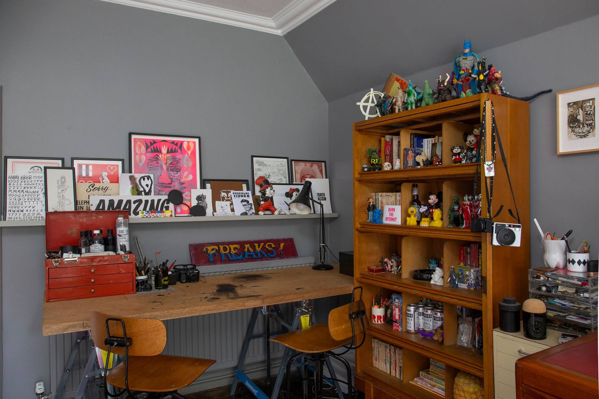 Creative studio room with a wooden work desk, shelving units, and art prints, Love Locations ME13.