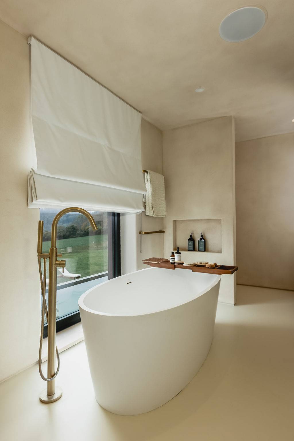 Luxury ensuite bathroom featuring a freestanding oval soaking bathtub set in front of floor-to-ceiling windows, Love Locations GU32.