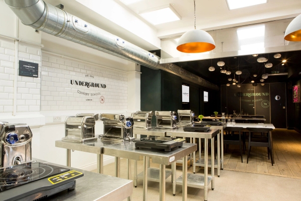 Underground cookery school film location featuring exposed ventilation pipes and clean metro tile walls, curated by Love Locations EC1V 1JN.