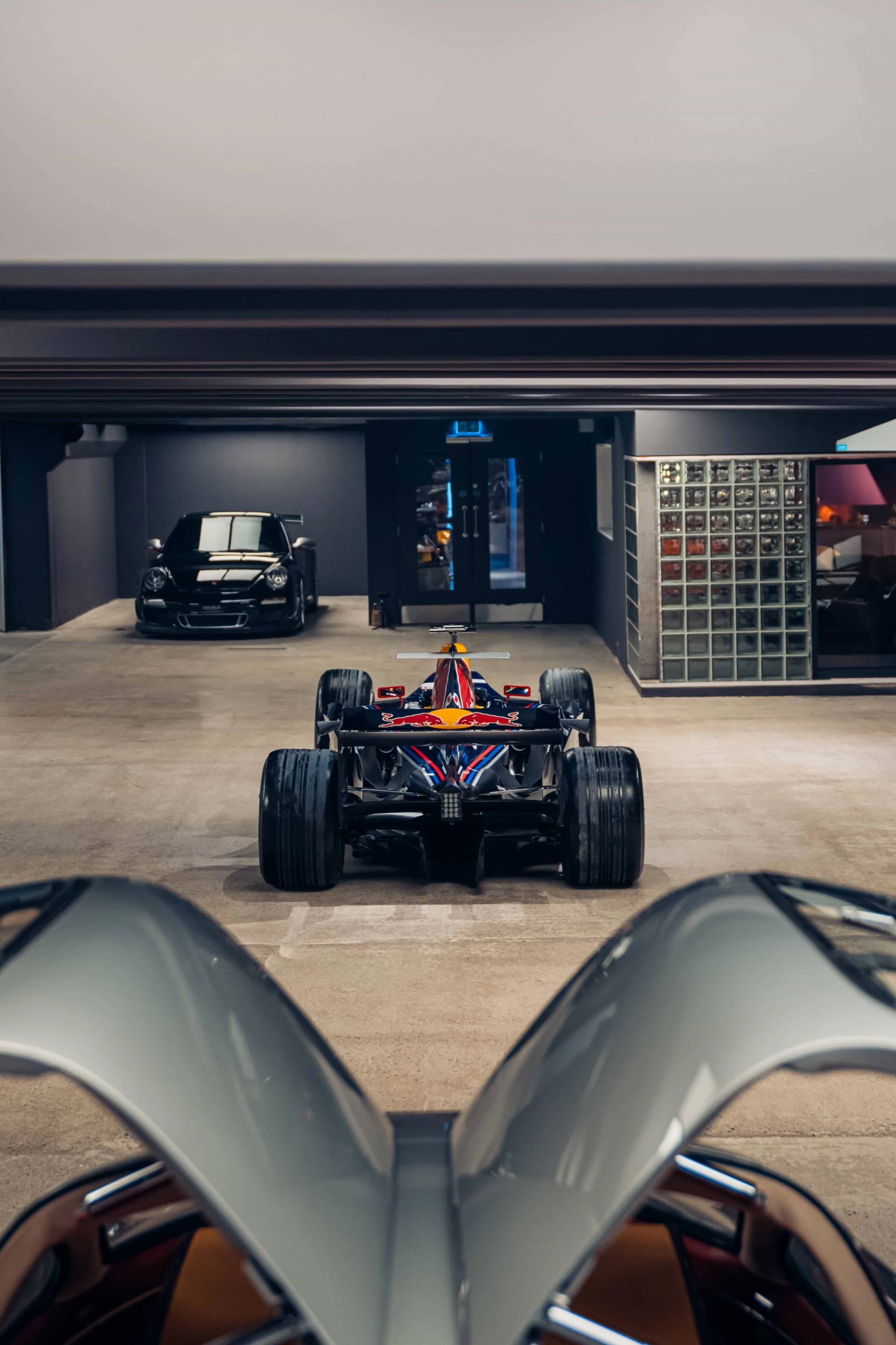 Rear view of a Formula 1 race car parked under sleek overhead lighting panels in a Brentford TW8 vault via Love Locations.