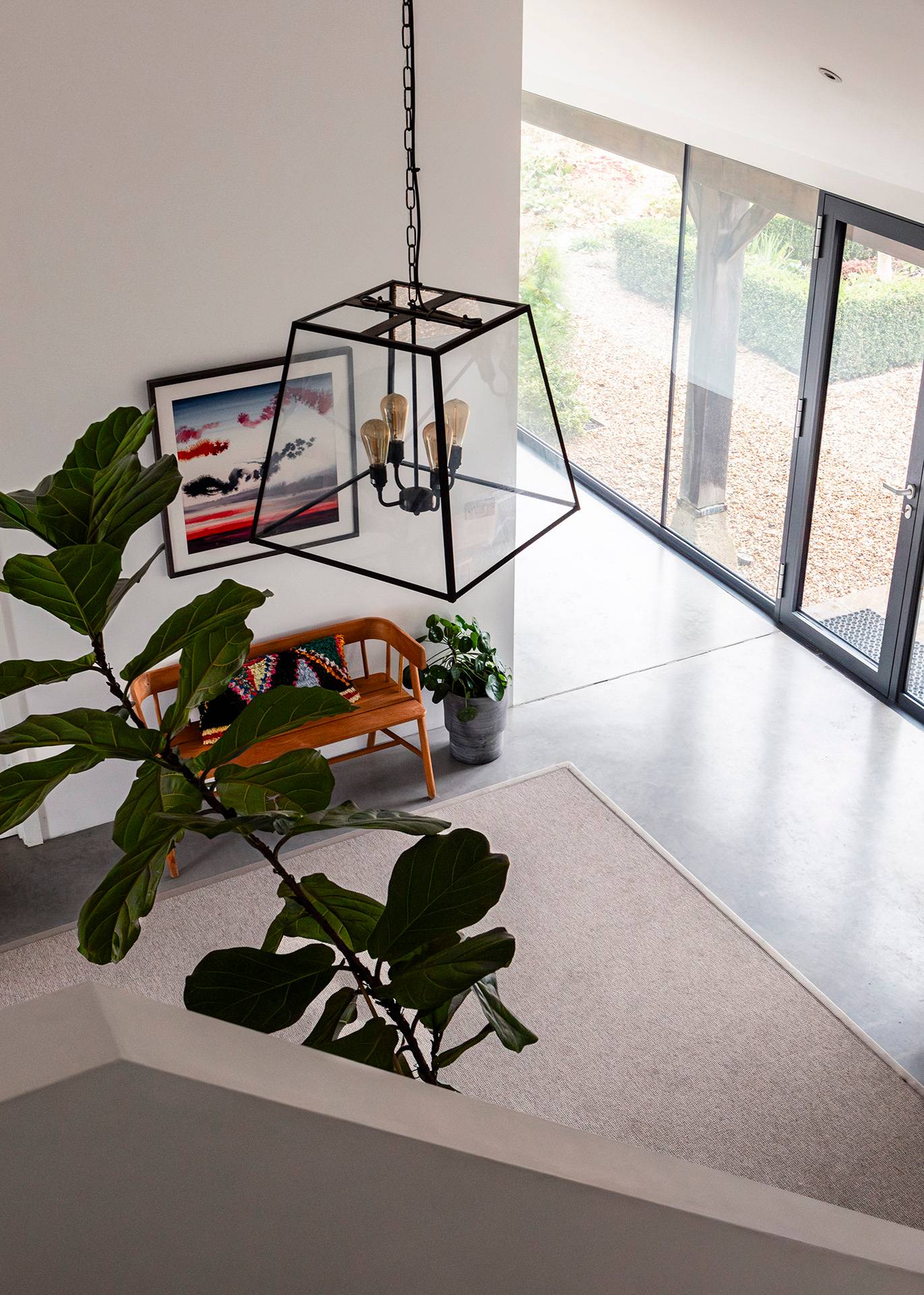 High-angle shot down into an inner hallway with a large potted plant, area rug, and metal lantern pendant light, Love Locations SN8.