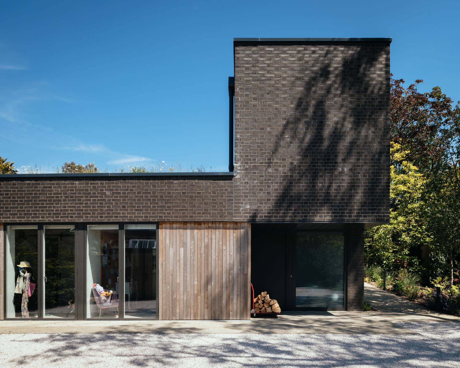 Dark brick architectural house extension with vertical timber panelling and large picture windows, Love Locations BN3.