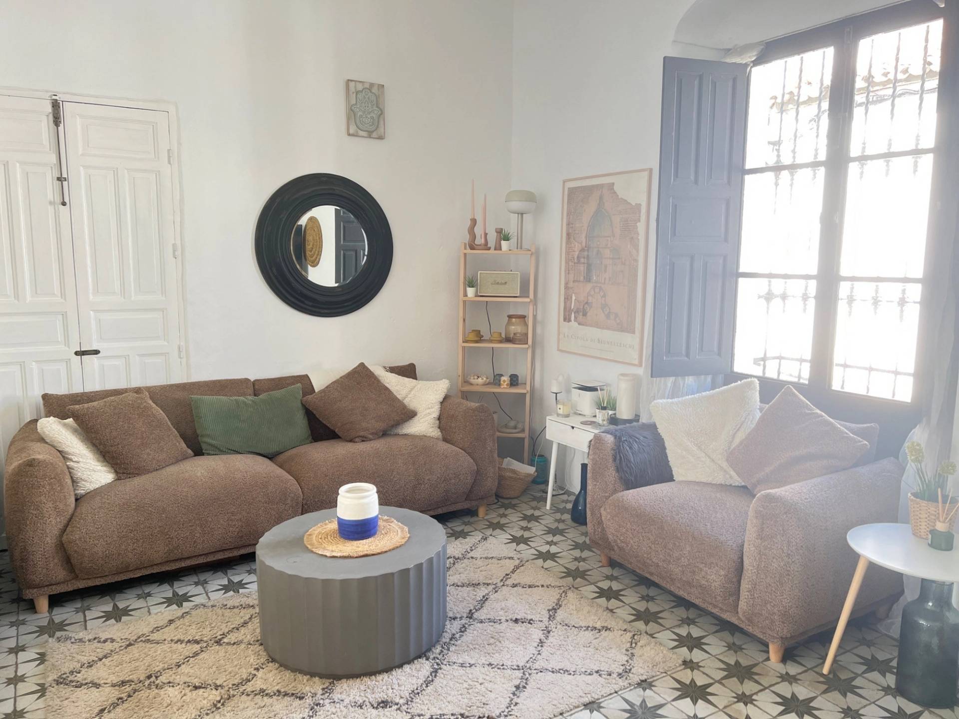 Warm living room photoshoot backdrop in Calle Sevilla Jimena de la Frontera by Love Locations, featuring a brown sofa, round coffee table, and large traditional window with shutters.