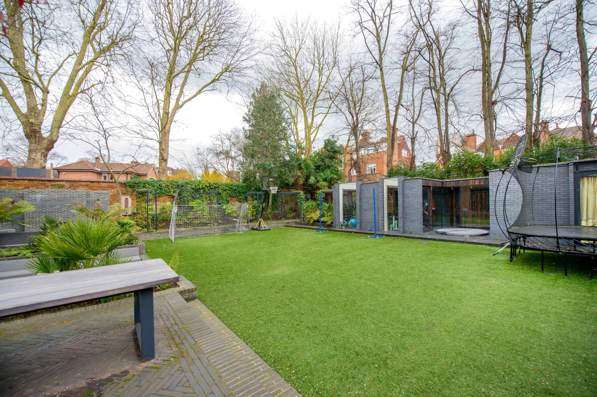 Spacious green lawn and garden view looking toward a modern garden outbuilding and boundary walls, Love Locations.