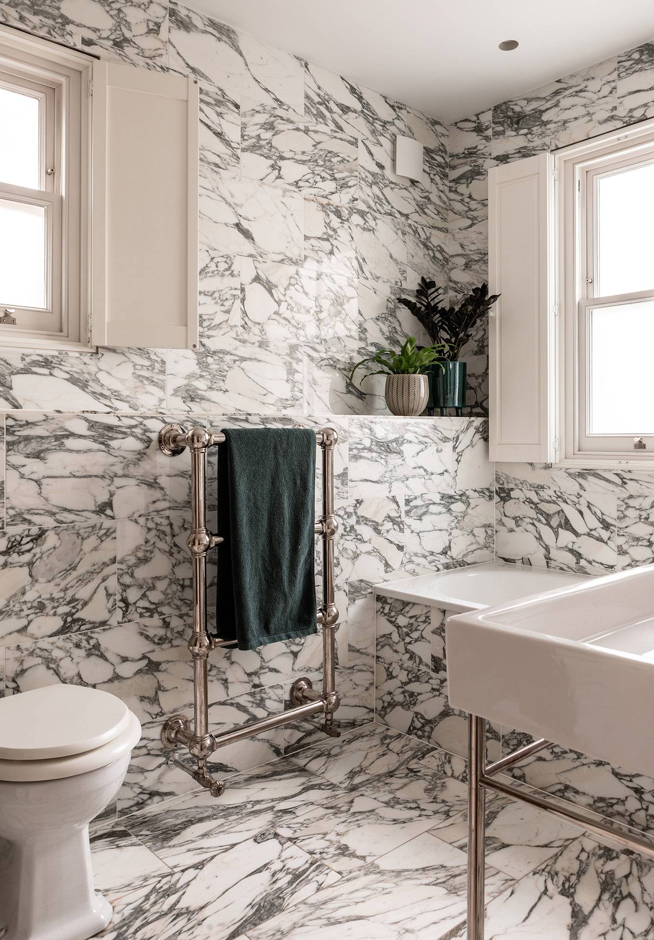 Close-up of a marble-clad bathroom soaking tub and period brass fixtures, ideal for luxury bath product campaigns, Love Locations.