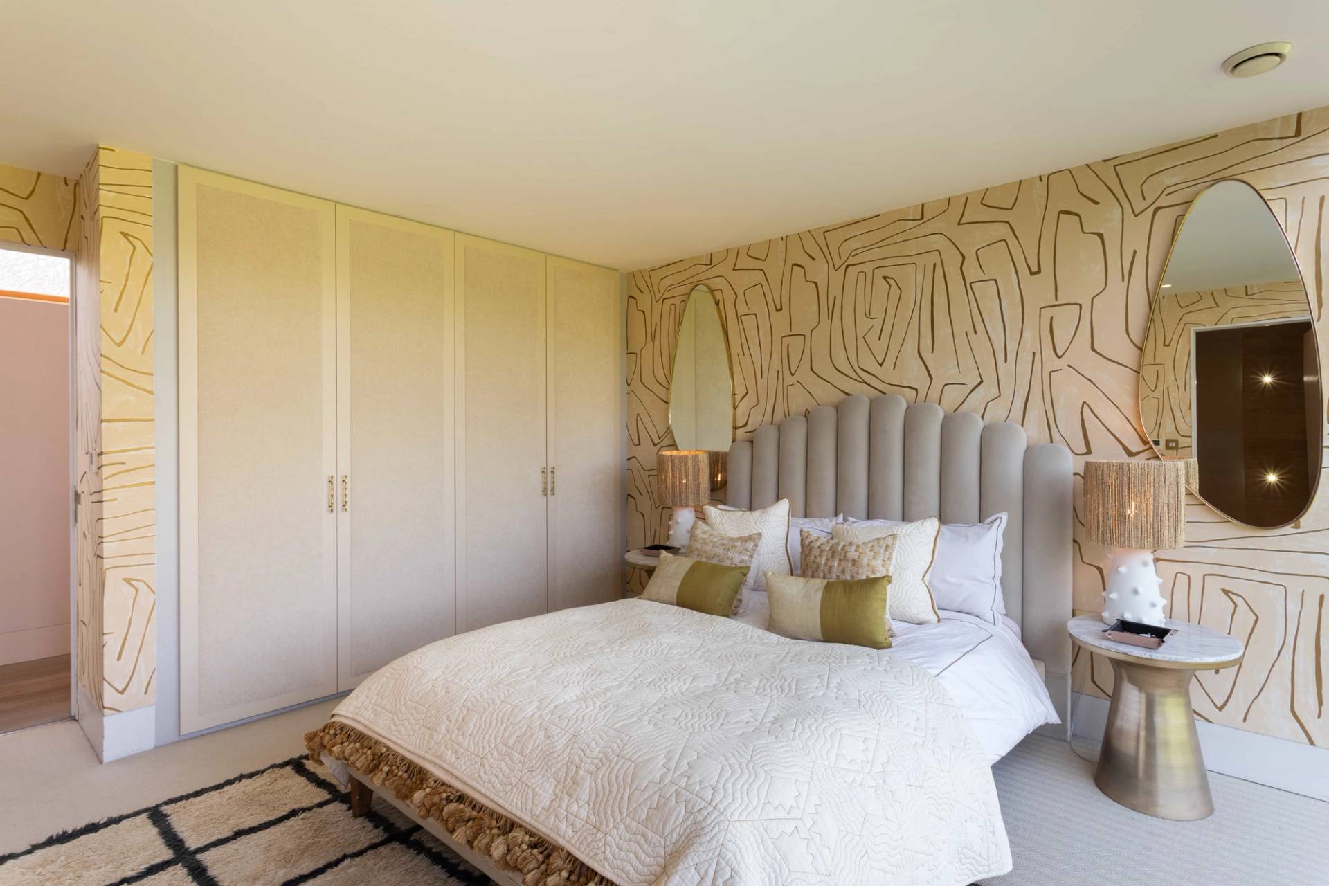 Love Locations editorial bedroom shoot space Surrey: Double bed styled with neutral linen tones against a striking graphic feature wall, ideal for home decor catalog photography.