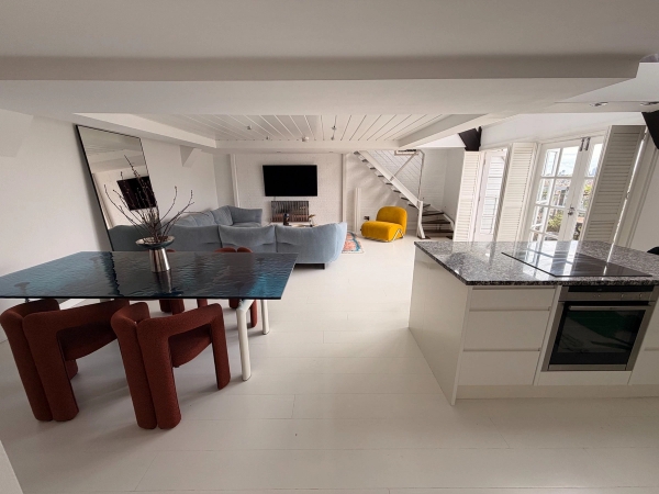 Expansive split-level penthouse living and kitchen area film location in Brixton SW4 by Love Locations, displaying polished light floors, modern furniture, and open architectural flow.