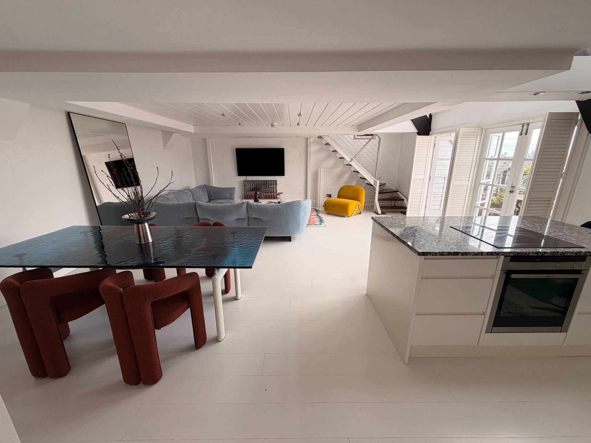 Expansive split-level penthouse living and kitchen area film location in Brixton SW4 by Love Locations, displaying polished light floors, modern furniture, and open architectural flow.