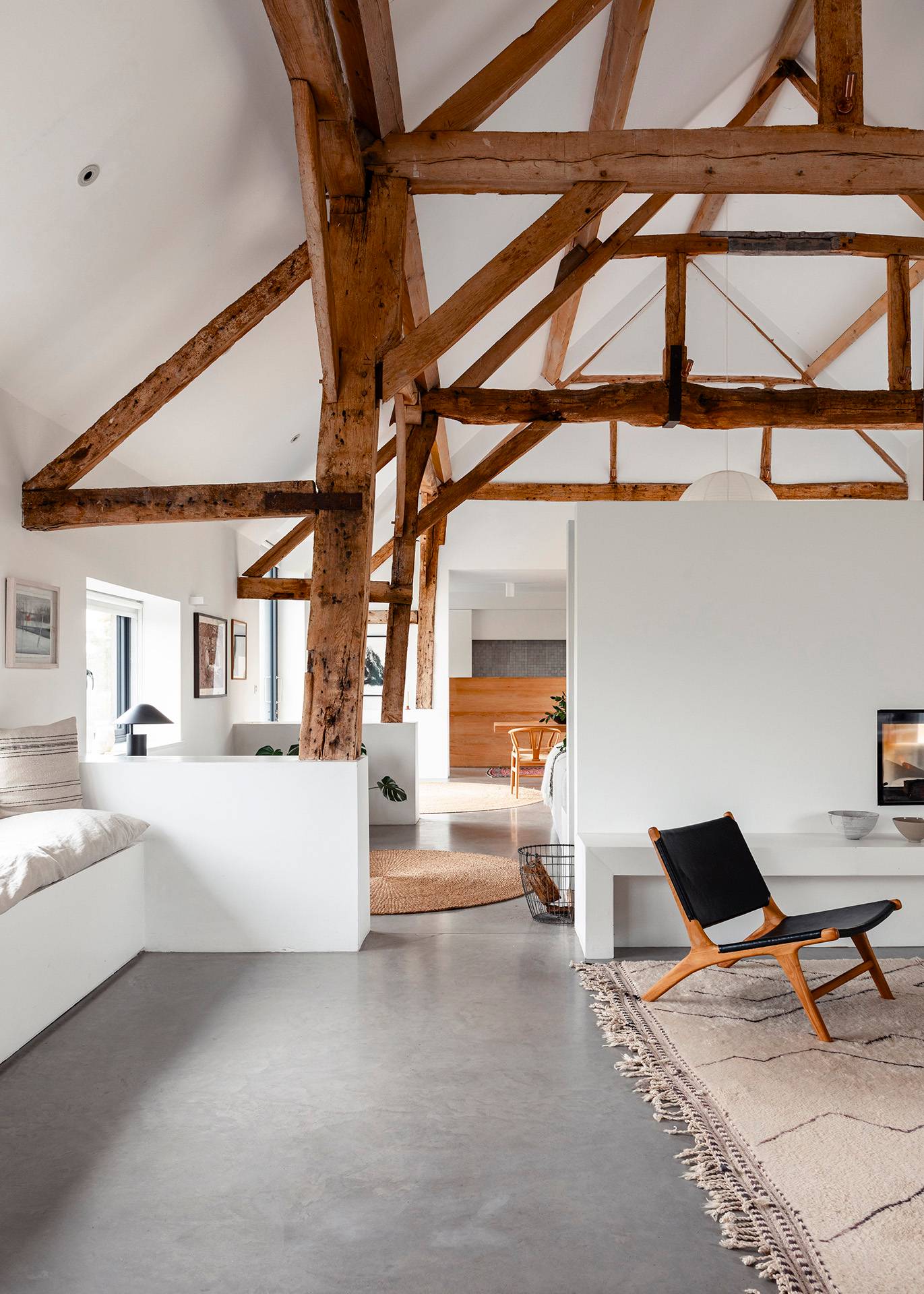 Lounge room transition looking past timber roof supports toward a white inset fireplace and polished concrete floor, Love Locations SN8.