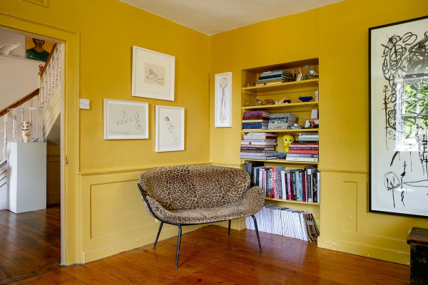 Yellow room nook set with a leopard print chair, open book display shelving, and framed art, Love Locations ME13.