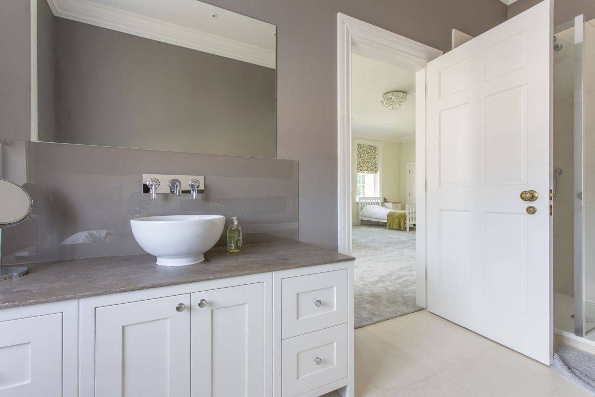 Modern luxury en-suite bathroom with a contemporary vessel sink looking through into a bright bedroom, Love Locations shoot venue.
