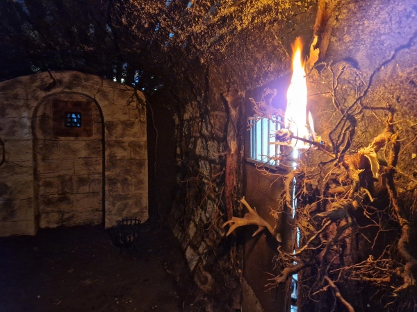Dark stone brick vault room lit by a flaming torch wall bracket for period filming, Love Locations BN8.