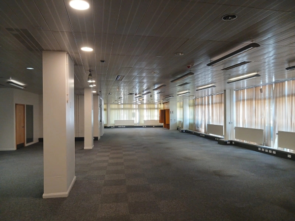 Moody, abandoned office interior shoot location in Watford WD18 from Love Locations, featuring a dark checkerboard carpet, grid ceiling tiles, and stark industrial lighting.