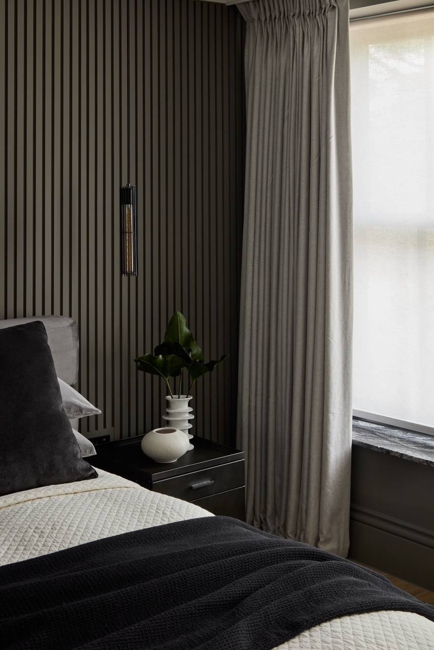 Detailed bedroom view highlighting integrated vertical wall slats, luxury soft furnishings, and natural window lighting, perfect for textile brand marketing, Love Locations.