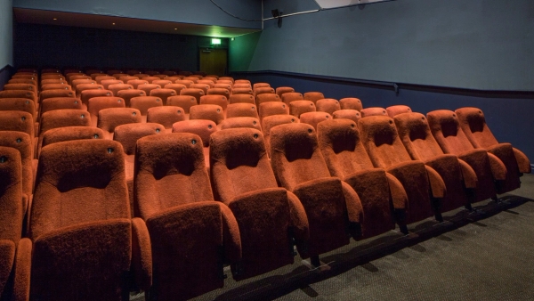 Close-up perspective of tiered red velvet theater seats and teal wall paneling inside The Ritzy Screen 4 shoot location in Brixton SW2 via Love Locations.