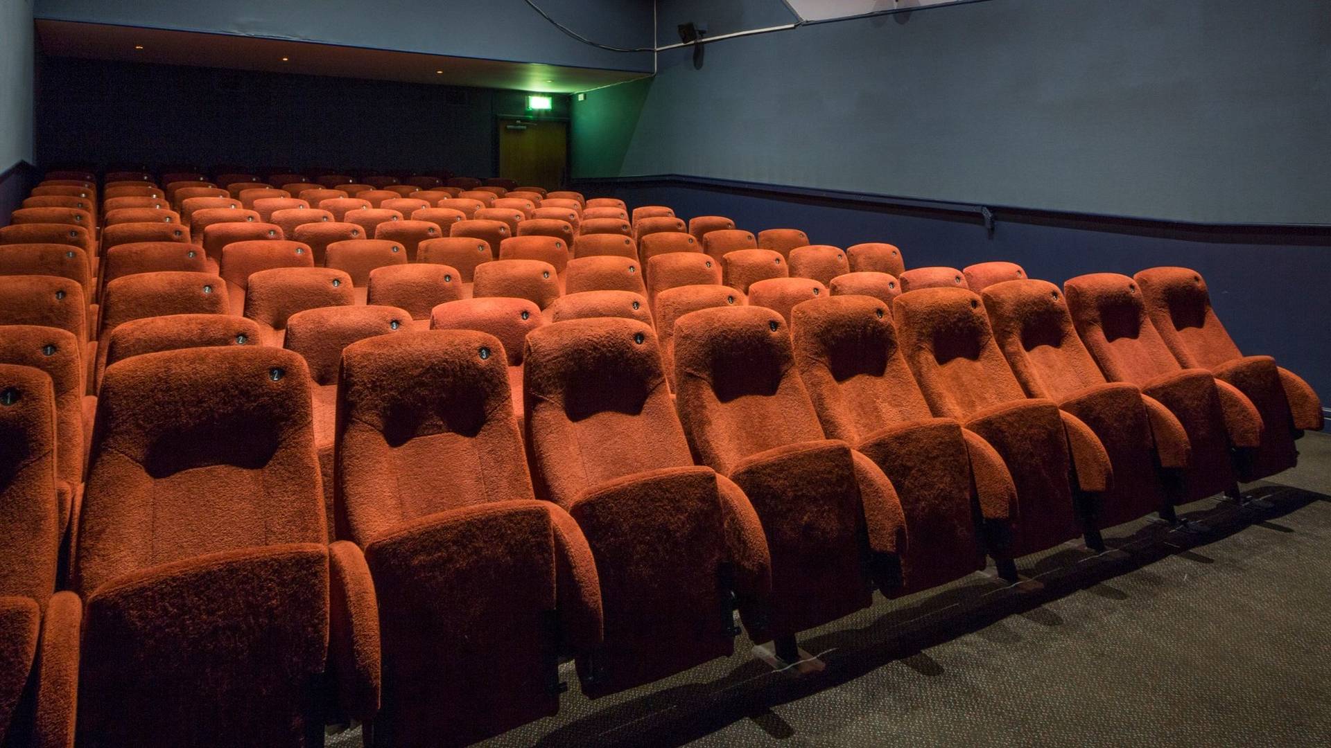Close-up perspective of tiered red velvet theater seats and teal wall paneling inside The Ritzy Screen 4 shoot location in Brixton SW2 via Love Locations.